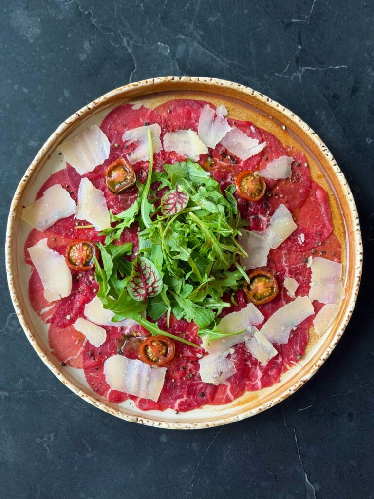 Carpaccio z rukolą, płatkami sera i pomidorkami